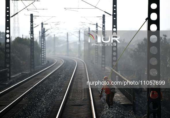 An overhead contact line worker at the Nanchang power supply section of China Southern Railway is hanging the ground wire at the Ruichang se...