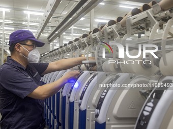 A worker is operating an intelligent production line at a textile company in Taizhou, Jiangsu Province, China, on March 12, 2024. (