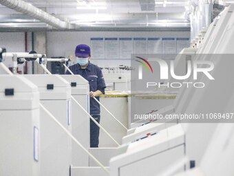 A worker is operating an intelligent production line at a textile company in Taizhou, Jiangsu Province, China, on March 12, 2024. (