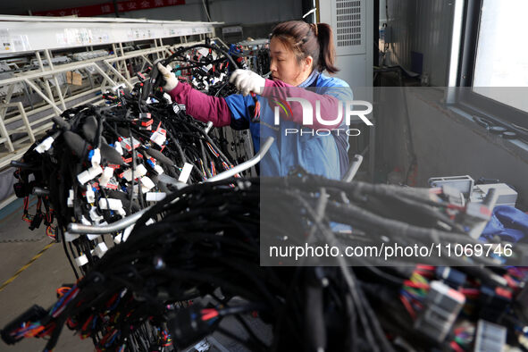 A worker is producing automotive wiring harness products at a workshop of an auto parts manufacturer in Binzhou, Shandong Province, China, o...