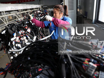 A worker is producing automotive wiring harness products at a workshop of an auto parts manufacturer in Binzhou, Shandong Province, China, o...