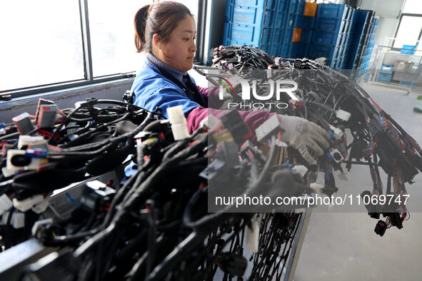 A worker is producing automotive wiring harness products at a workshop of an auto parts manufacturer in Binzhou, Shandong Province, China, o...