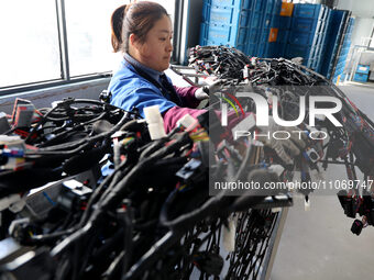 A worker is producing automotive wiring harness products at a workshop of an auto parts manufacturer in Binzhou, Shandong Province, China, o...