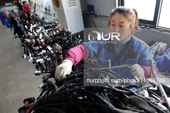 A worker is producing automotive wiring harness products at a workshop of an auto parts manufacturer in Binzhou, Shandong Province, China, o...