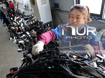 A worker is producing automotive wiring harness products at a workshop of an auto parts manufacturer in Binzhou, Shandong Province, China, o...