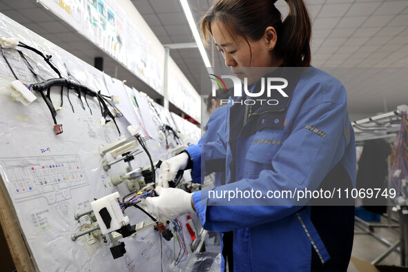 A worker is producing automotive wiring harness products at a workshop of an auto parts manufacturer in Binzhou, Shandong Province, China, o...