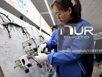 A worker is producing automotive wiring harness products at a workshop of an auto parts manufacturer in Binzhou, Shandong Province, China, o...