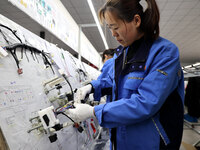 A worker is producing automotive wiring harness products at a workshop of an auto parts manufacturer in Binzhou, Shandong Province, China, o...