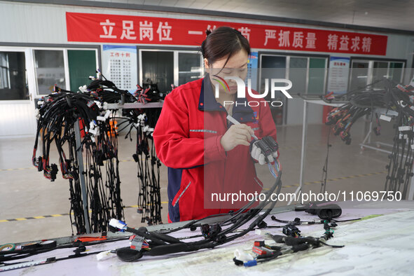 A worker is producing automotive wiring harness products at a workshop of an auto parts manufacturer in Binzhou, Shandong Province, China, o...