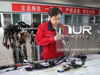 A worker is producing automotive wiring harness products at a workshop of an auto parts manufacturer in Binzhou, Shandong Province, China, o...