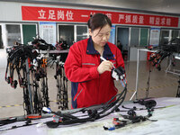 A worker is producing automotive wiring harness products at a workshop of an auto parts manufacturer in Binzhou, Shandong Province, China, o...