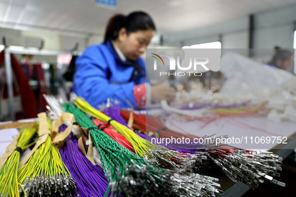 A worker is producing automotive wiring harness products at a workshop of an auto parts manufacturer in Binzhou, Shandong Province, China, o...