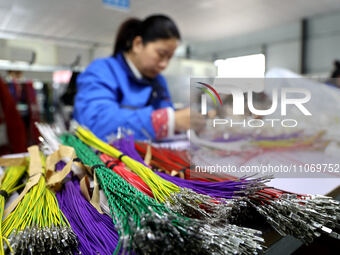 A worker is producing automotive wiring harness products at a workshop of an auto parts manufacturer in Binzhou, Shandong Province, China, o...