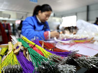 A worker is producing automotive wiring harness products at a workshop of an auto parts manufacturer in Binzhou, Shandong Province, China, o...