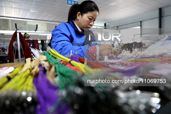 A worker is producing automotive wiring harness products at a workshop of an auto parts manufacturer in Binzhou, Shandong Province, China, o...