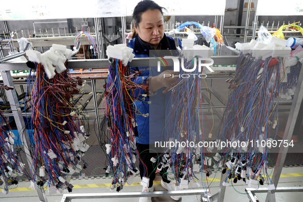 A worker is producing automotive wiring harness products at a workshop of an auto parts manufacturer in Binzhou, Shandong Province, China, o...