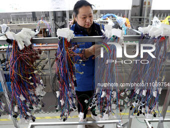 A worker is producing automotive wiring harness products at a workshop of an auto parts manufacturer in Binzhou, Shandong Province, China, o...