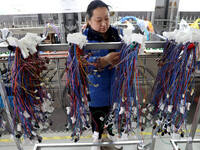 A worker is producing automotive wiring harness products at a workshop of an auto parts manufacturer in Binzhou, Shandong Province, China, o...