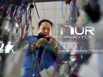 A worker is producing automotive wiring harness products at a workshop of an auto parts manufacturer in Binzhou, Shandong Province, China, o...