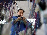 A worker is producing automotive wiring harness products at a workshop of an auto parts manufacturer in Binzhou, Shandong Province, China, o...