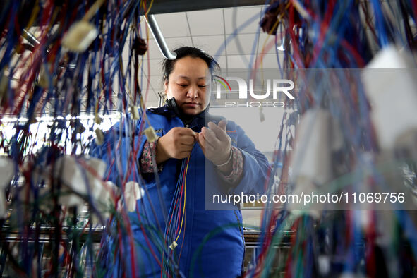 A worker is producing automotive wiring harness products at a workshop of an auto parts manufacturer in Binzhou, Shandong Province, China, o...