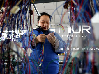 A worker is producing automotive wiring harness products at a workshop of an auto parts manufacturer in Binzhou, Shandong Province, China, o...