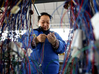 A worker is producing automotive wiring harness products at a workshop of an auto parts manufacturer in Binzhou, Shandong Province, China, o...