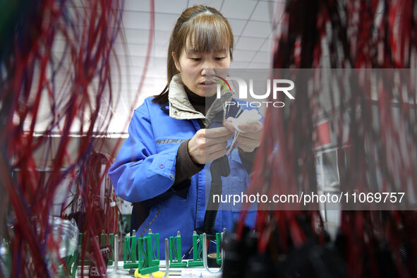 A worker is producing automotive wiring harness products at a workshop of an auto parts manufacturer in Binzhou, Shandong Province, China, o...