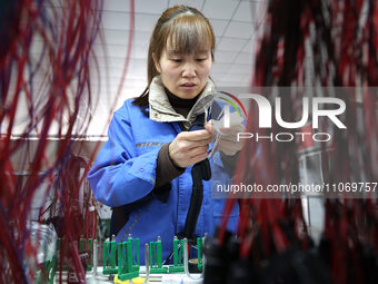 A worker is producing automotive wiring harness products at a workshop of an auto parts manufacturer in Binzhou, Shandong Province, China, o...