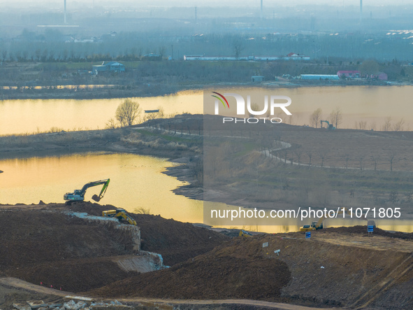 Construction workers and large machinery are working on the Heilongtan Reservoir reinforcement project in Lianyungang, China, on March 12, 2...