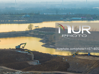 Construction workers and large machinery are working on the Heilongtan Reservoir reinforcement project in Lianyungang, China, on March 12, 2...