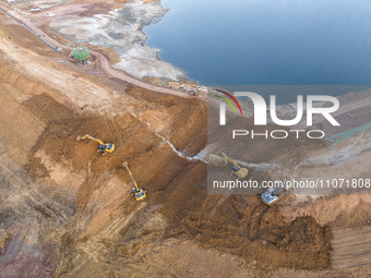 Construction workers and large machinery are working on the Heilongtan Reservoir reinforcement project in Lianyungang, China, on March 12, 2...