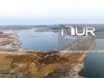 Construction workers and large machinery are working on the Heilongtan Reservoir reinforcement project in Lianyungang, China, on March 12, 2...