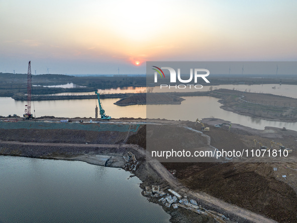 Construction workers and large machinery are working on the Heilongtan Reservoir reinforcement project in Lianyungang, China, on March 12, 2...