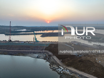 Construction workers and large machinery are working on the Heilongtan Reservoir reinforcement project in Lianyungang, China, on March 12, 2...