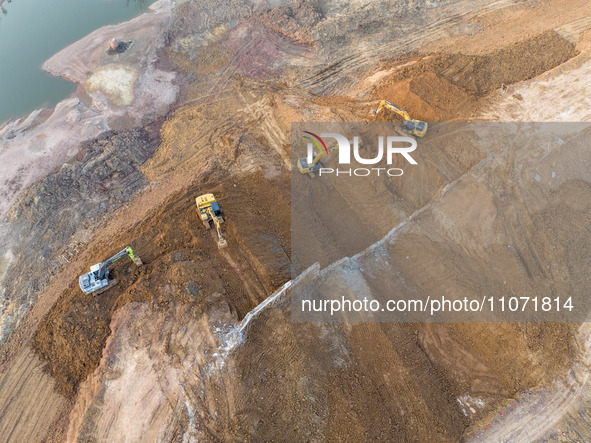 Construction workers and large machinery are working on the Heilongtan Reservoir reinforcement project in Lianyungang, China, on March 12, 2...