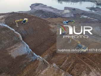 Construction workers and large machinery are working on the Heilongtan Reservoir reinforcement project in Lianyungang, China, on March 12, 2...