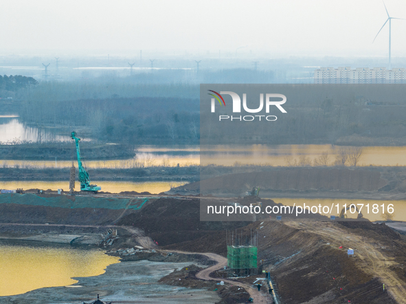 Construction workers and large machinery are working on the Heilongtan Reservoir reinforcement project in Lianyungang, China, on March 12, 2...