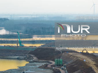 Construction workers and large machinery are working on the Heilongtan Reservoir reinforcement project in Lianyungang, China, on March 12, 2...