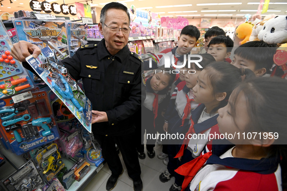 A staff member from the Trade branch of the Handan District Market Supervision Bureau is instructing primary school students on how to ident...