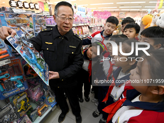 A staff member from the Trade branch of the Handan District Market Supervision Bureau is instructing primary school students on how to ident...