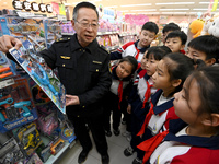 A staff member from the Trade branch of the Handan District Market Supervision Bureau is instructing primary school students on how to ident...