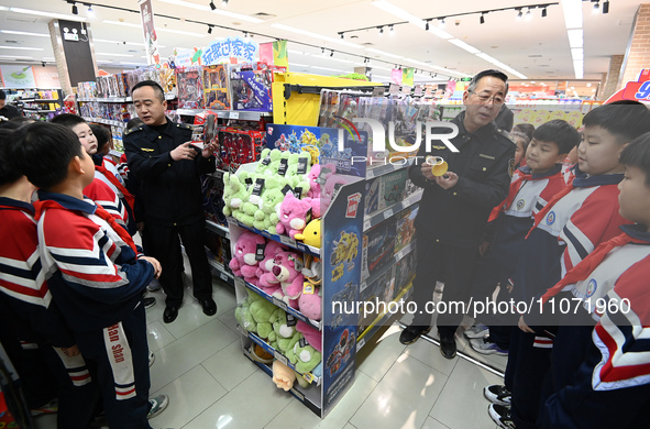 A staff member from the Trade branch of the Handan District Market Supervision Bureau is instructing primary school students on how to ident...