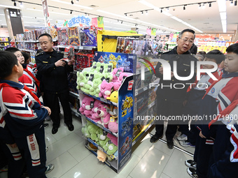 A staff member from the Trade branch of the Handan District Market Supervision Bureau is instructing primary school students on how to ident...