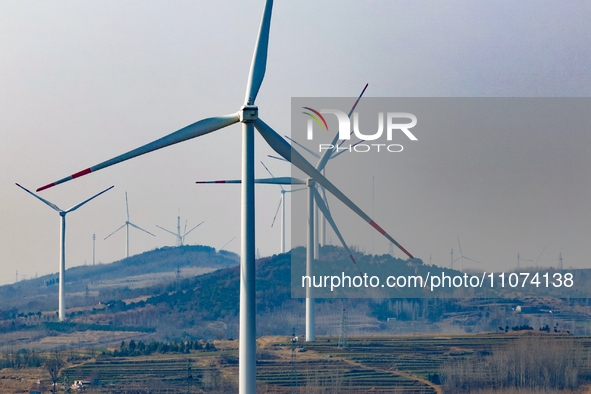 Giant windmills are spinning in the wind at Baoshan Town wind farm in the West Coast New Area of Qingdao, Shandong Province, China, on March...