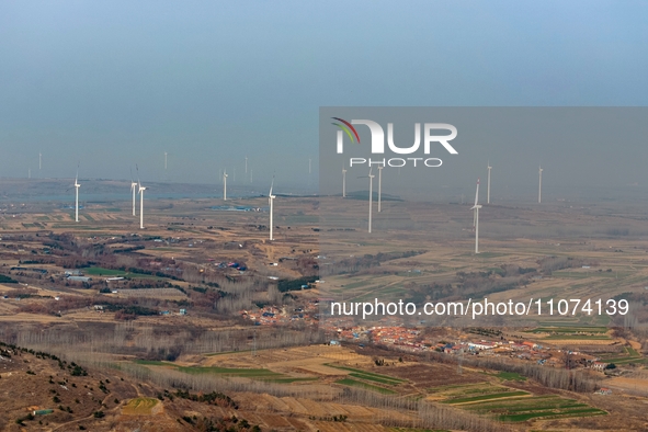 Giant windmills are spinning in the wind at Baoshan Town wind farm in the West Coast New Area of Qingdao, Shandong Province, China, on March...