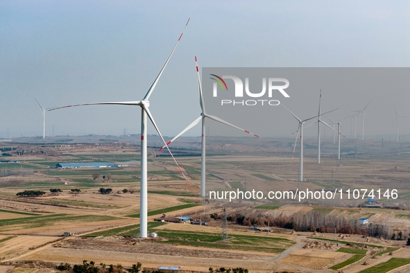 Giant windmills are spinning in the wind at Baoshan Town wind farm in the West Coast New Area of Qingdao, Shandong Province, China, on March...