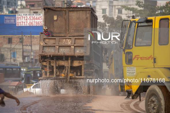 A worker is spraying water from a truck to control dust in a polluted area in Dhaka, Bangladesh, on March 16, 2024. 