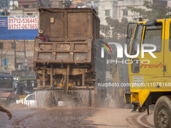 A worker is spraying water from a truck to control dust in a polluted area in Dhaka, Bangladesh, on March 16, 2024. (