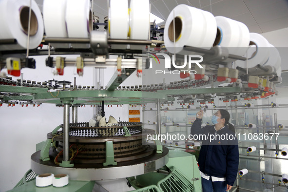 A worker is producing textile foreign trade products on a workshop production line at a spandex company workshop in the Lianyungang Economic...